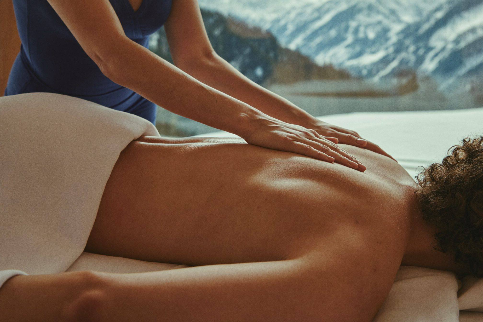 Therapist performing a deep tissue shoulder massage in warm alpine light